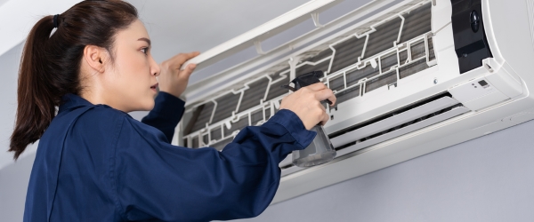 female technician service cleaning air conditioner indoors